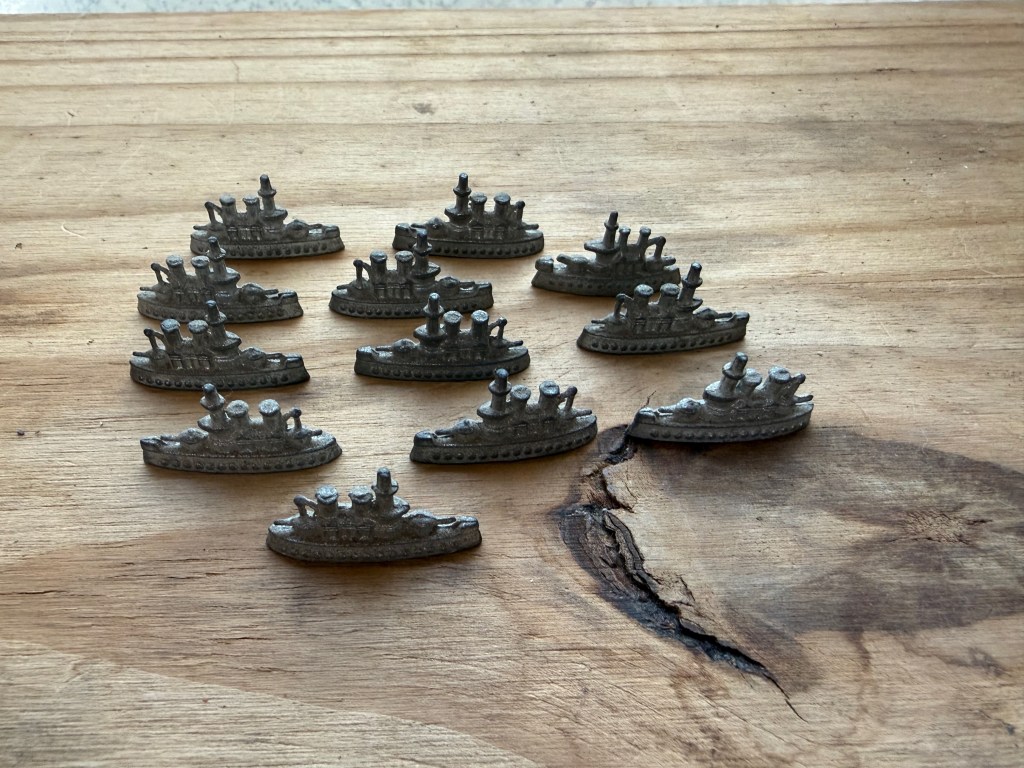 A collection of ten metallic ship models arranged on a wooden surface.
