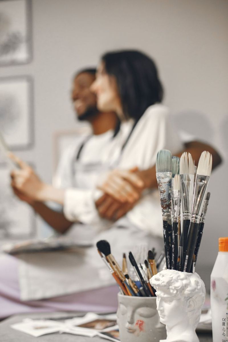 paintbrushes and woman and man in background